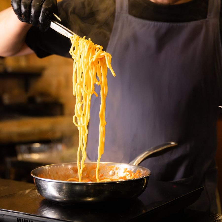 Cozinheiro tira o macarrão da frigideira